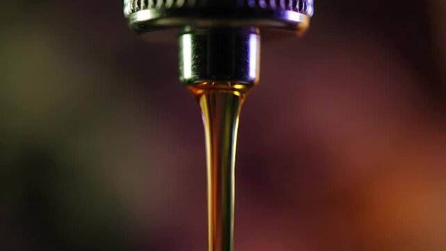Close-up of CBD oil drop from vape cartridge with purple and blue background.