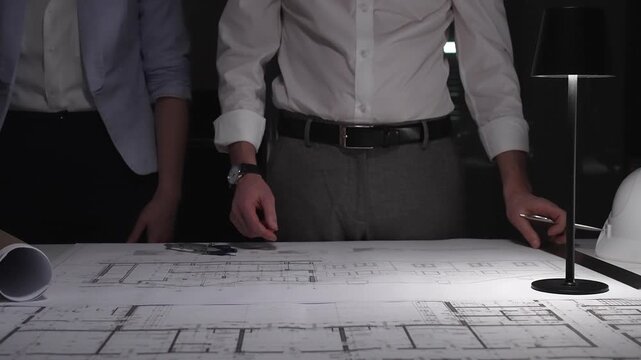 Architects and engineers collaborating on blueprint plans, working together on an architecture project layout design late at night.