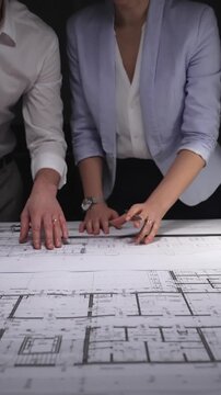 Architects and engineers collaborating on a building blueprint, measuring and discussing plans for a new construction project. Concept of architecture and business in low key lighting