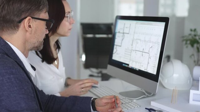 Architecture and engineering team collaborating on project blueprints using computer aided design software in an office. Business and architecture concept