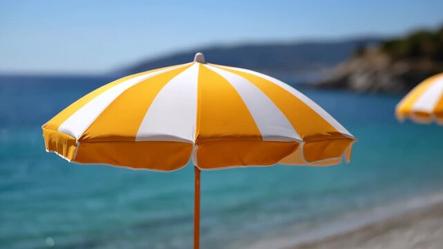 Golden Sunshade at the Seaside: A vibrant striped sunshade against the azure sea, evokes a sense of leisurely relaxation on a bright, sunny day at the seaside. The foreground features the sunshade.
