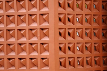 Naklejka premium Brick red rooster wall texture with a geometric pattern. This ventilation block background features a repeating 3D square design, perfect for architectural and graphic elements.