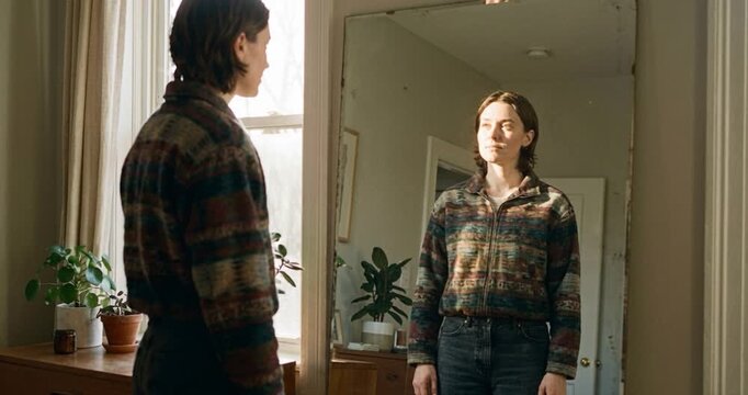 Person contemplating reflection in mirror in bright interior