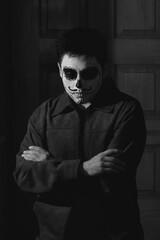 Obraz premium Person with face paint stands with arms crossed in front of a wooden wall