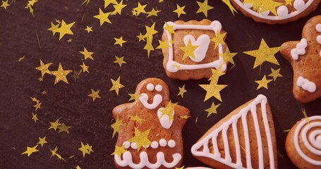 Obraz premium Featuring gingerbread person cookie iced with white on dark slate, amid cookies and gold stars