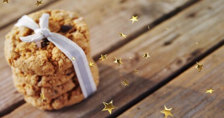 Obraz premium Displaying oatmeal cookie stack tied with pale ribbon on worn wooden plank, gold stars, copy space