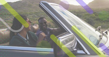 Driving convertible pair laughing and gesturing along hilly road, in shades, green jacket, overlays