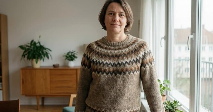 Woman in sweater standing indoors by window