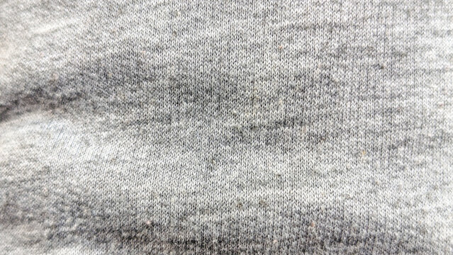 A close-up texture of gray melange cotton knit fabric. The surface shows a soft, heathered pattern with delicate horizontal and vertical weaves, typical of a jersey or sweatshirt material.