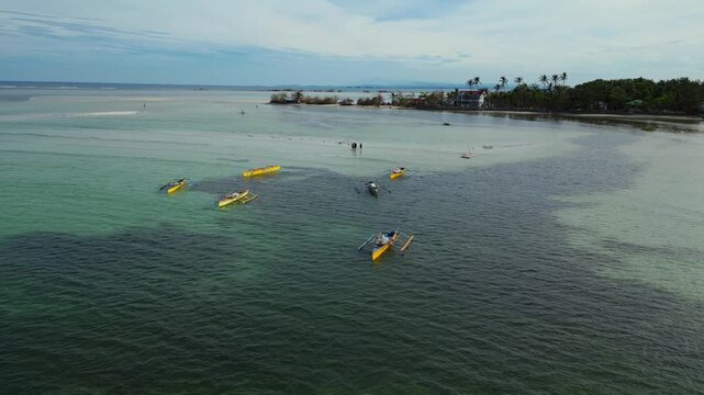 Diagonal aerial capturing palm-lined shore, gentle waves, and a resting boat along Tondol Beach in Anda.