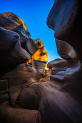 Narrow canyon with smooth rock walls and bright blue sky above showing natural potholes in stone Lei Dan Stone Field Thailand