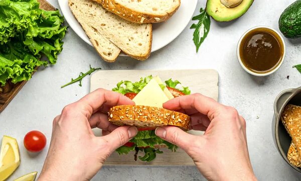 Hands preparing fresh healthy sandwich with cheese and vegetables