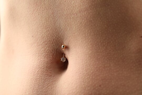 Woman with belly button piercing, closeup view