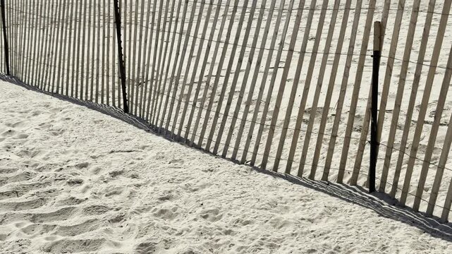 Abstract shadow patterns through wooden beach fence on sand