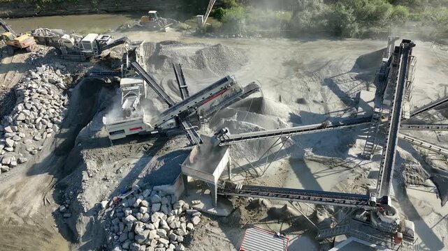 Aerial drone video of Gravel separator machine separates stone material into various fractions. Stone crusher plant machine. Conveyor belt in work process. Extraction of aggregates or gold from river