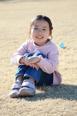 芝生に体育座りする女の子