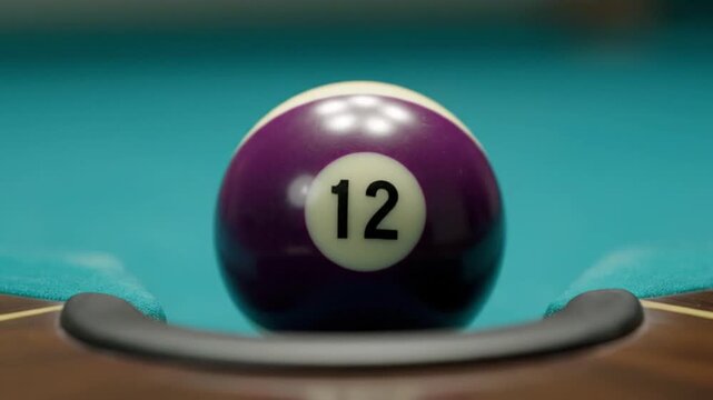 A purple number 12 billiard ball poised at the edge of a pool table pocket.