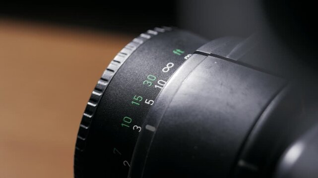 Close up of lens focus ring rotating across distance scale back and forth