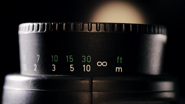 Backlit front view of focus ring with feet and meters turning back and forth adjusting focus distance