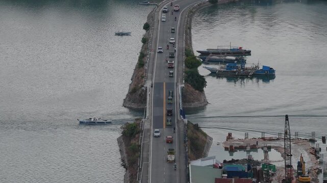 Causeway bridge spans blue water linking Tagbilaran City and Dauis town with marine and land traffic crossing, aerial static
