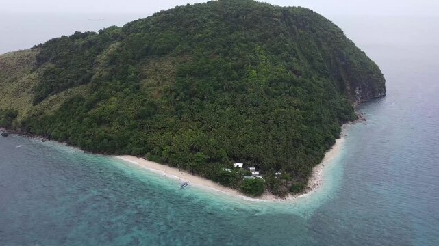 Drone footage of a white beach island in one of the most unsaturated islands in the Philippines. The white sand is visible on the corner of the island. Perfect place to go for swimming and diving.