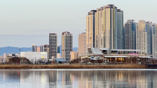 Daegu, South Korea &ndash; February 8, 2026: City buildings of Daegu are reflected on the frozen surface of Suseong Lake during winter. Pedestrians walk along the shoreline