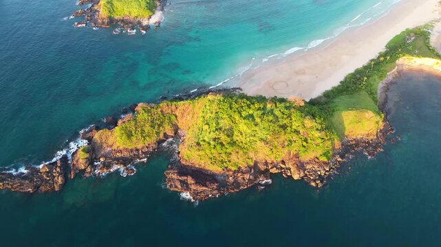 Cinematic top-down aerial drone shot of the lush green peninsula separating the twin beaches of Nacpan in El Nido, Palawan. Pristine tropical coastline in the Philippines