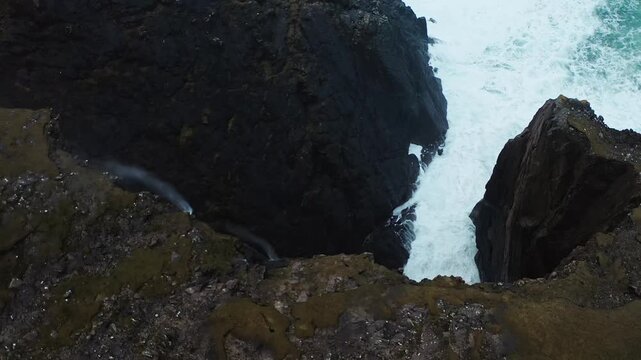 Drone shot of a coastal waterfall being blown uphill during strong winds.