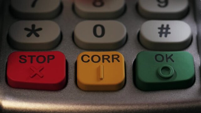 Close up of finger pressing stop, corr and ok keys on terminal keypad
