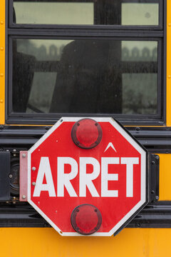 Canada, Quebec, 27 November 2025 : French stop sign attached to yellow school bus in urban setting