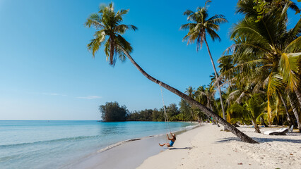 Naklejka premium Relaxing on a tranquil swing at Khlong Hin Beach, Koh Kood, Thailand under the bright blue sky