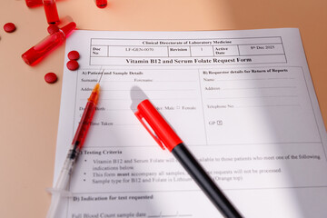 Obraz premium Vitamin B12 vials with red tablets and blood test form on cream gradient for metabolic health, energy recovery and professional wellness.