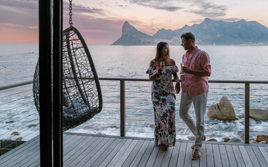 Fototapeta premium Charming couple enjoying sunset drinks on a waterfront deck in Cape Town, South Africa