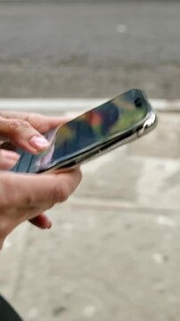 Woman using a smartphone while walking in an urban street, vertical shot