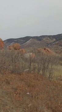 Rocky Foothills with Red Sandstone and Patchy Snow under Overcast Sky