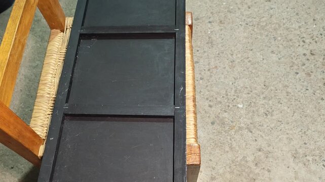 Close up of hand holding a manual staple gun against a black surface.