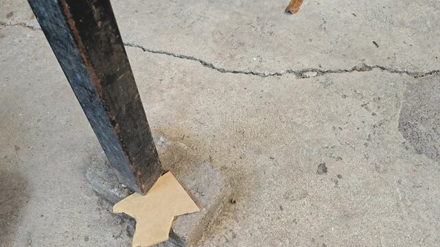 Inserting a wooden wedge into a metal pipe base on the floor.