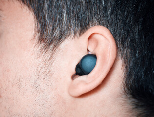 Person using wireless earbud for listening to audio