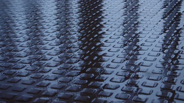 Symmetrical shadows of two people walking across a wet cobblestone pavement. Abstract urban scene with reflections, movement and anonymous human presence after rain.