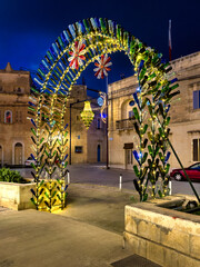 Ghajnsielem, Gozo, Malta- Illuminated Christmas arch made of colorful glass bottles with floral ornaments in Ghajnsielem on the island of Gozo