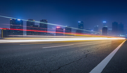 Obraz premium Long exposure car light trails near urban buildings, ideal for transportation, cityscape, night photography, motion blur concepts in design projects.