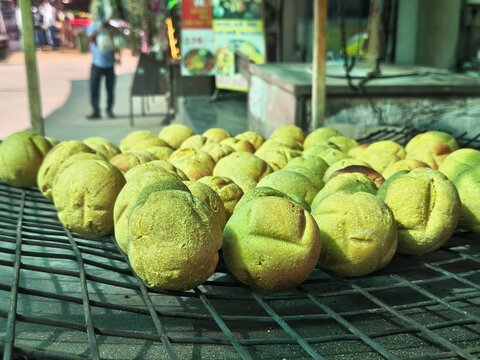 Traditional bati roasting on grill at a street stall, classic rajasthani marwari cuisine served with daal, showcasing rustic Indian food culture, golden baked wheat balls popular in local markets here
