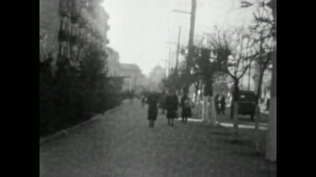 People walking slowly along quiet city street, moving through calm urban day in winter mood. Everyday life, peaceful rhythm, nostalgic moment. Old film. Archival retro. Vintage archive. 1960s Ukraine