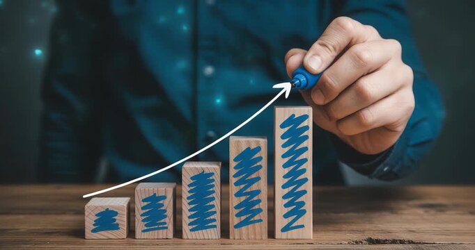 Businessman drawing growth chart with marker on wooden blocks