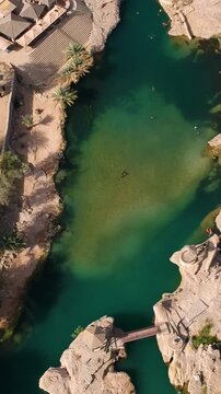 Vertical aerial of beautiful Wadi Bani Khalid oasis with turquoise water, hidden river and palm trees in the Sultanate of Oman.