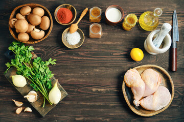 Raw chicken legs, mushrooms and vegetables - ingredients for cooking on wooden table with copy space