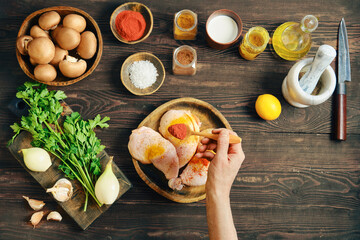 Hand sprinkle smoked paprika over raw chicken thighs making dry marinade