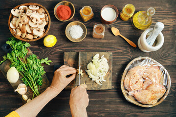 Top view of hands chopping fresh garlic on a wooden cutting board