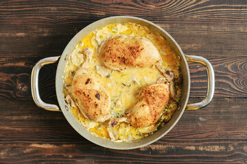 Top view of chicken legs in a pot with creamy sauce on a wooden table