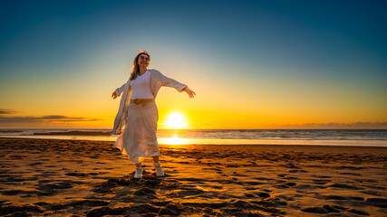 Fototapeta premium Beautiful middle-aged woman enjoying walk on sandy beach on sunset on windy spring day. Front view 